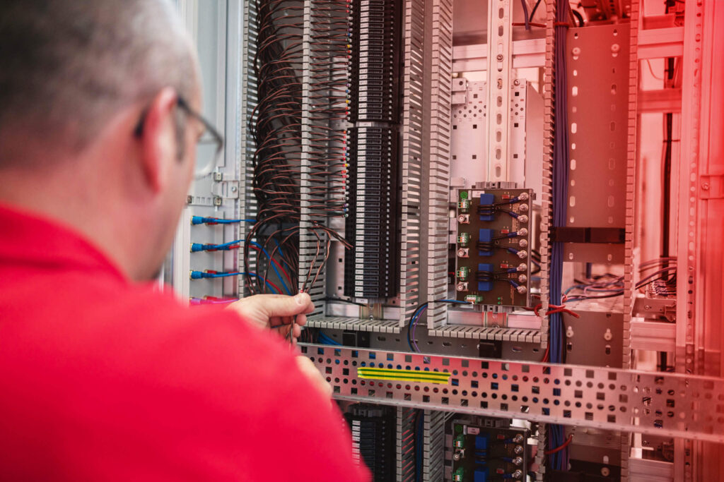 Mitarbeiter arbeit an einem Schaltschrank, Blick über die Schulter