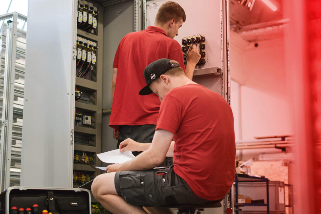 Zwei hse Techniker arbeiten an einem Schaltschrank.